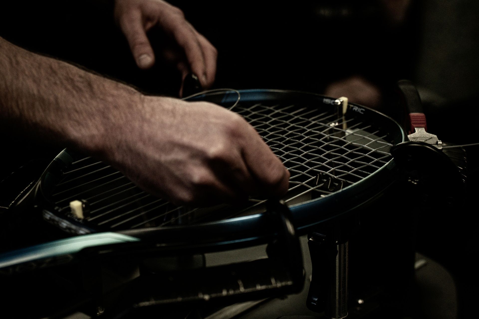 Close-up shot focused on precise stringing of a tennis racket, showing detailed craftsmanship.